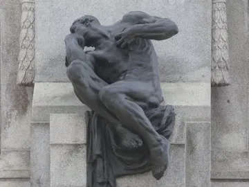 Detail of the Antonio Maceo Monument showing a seated bronze figure in a pensive pose against a carved stone backdrop.