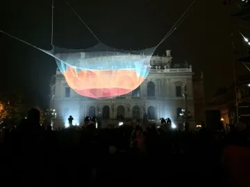 Janet Echelman’s 1.26 suspended above a crowd at night, with a lit neoclassical building in the background.
