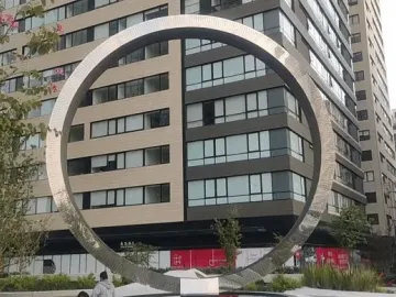The Eye of Mexico circular metal sculpture framed against tall residential buildings.