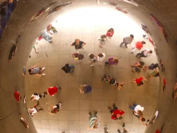 Crowd reflections distorted on Cloud Gate\'s polished concave surface.