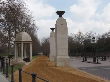 Commonwealth Memorial Gates with stone pillars, urns, and a domed pavilion beside a paved path.