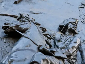 Bronze relief from the Monument to Peter I showing a horseman in historical military attire and a tricorn hat.