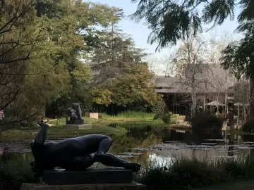 The River, a dark reclining nude female sculpture on a stone plinth outdoors.