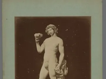 Marble statue of Bacchus with a small satyr at his side, holding a cup and wearing a grape wreath.