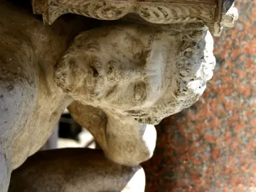 Close-up of Il Gobbo di Rialto showing the weathered stone head and hunched upper body beneath an ornate carved structure.