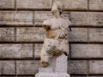 Pasquino, a weathered stone statue on a pedestal beside a post covered with handwritten notes.
