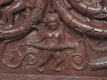 Close-up of the Sarcophagus of Constantina showing a winged putto holding a garland among intertwined relief figures and sea creatures.