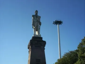 Monument to General Carlos M. de Alvear on a dark pedestal, with a tall white pole and trees beside it.