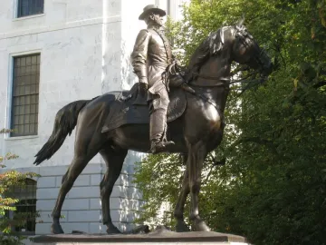 General Joseph Hooker statue on horseback beside a stone building and trees