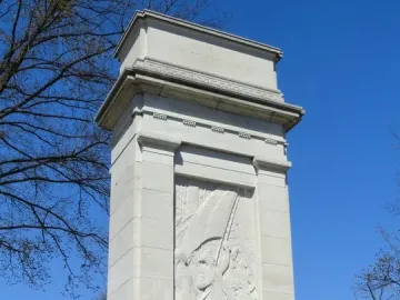 John Paul Jones Memorial with a tall stone shaft, relief figures, and decorative friezes against a blue sky.