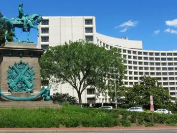 Major General George B. McClellan equestrian statue on a carved stone base, with a curved hotel building behind it.