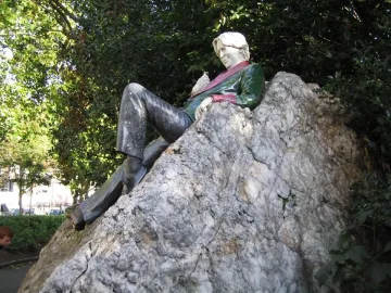 Oscar Wilde Memorial Sculpture of a reclining figure with light hair on a large rocky boulder.