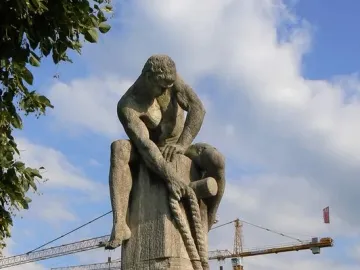 Tauzieher stone sculpture of a muscular man pulling a rope around a stone post.
