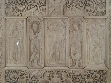 Relief panel from the Throne of Maximian with five haloed figures in vertical sections, surrounded by carved vines and animals.