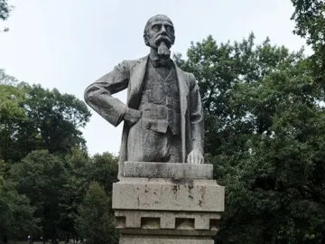 Stone bust of Ernesto Teodoro Moneta on a pedestal in a grassy park
