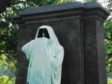Eternal Silence sculpture, a hooded bronze figure standing before a dark stone slab.