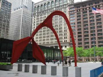 Flamingo, a large bright red abstract sculpture in a city plaza with tall buildings behind it.
