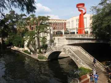 La Antorcha de la Amistad rising above a stone bridge in downtown San Antonio.