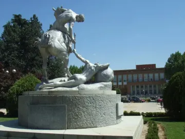 The Torch Bearers monument shows a nude rider on horseback passing a torch to a prone figure on a circular pedestal.