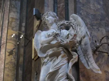 Bernini\'s Angel with the Crown of Thorns, a white marble angel holding a thorny wreath and looking upward.