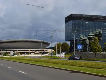 Silesian Insurgents\' Monument seen behind trees and road signs, with a glass skyscraper in the background.