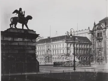 Schiller Monument with a winged figure riding a panther atop a tall pedestal, surrounded by classical statues and historic buildings.