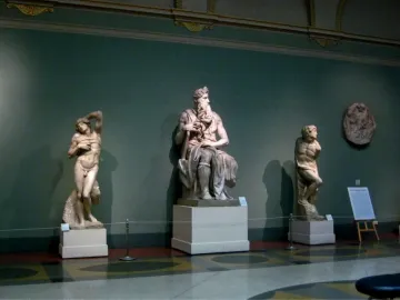 The Taddei Tondo relief sculpture displayed on a dark green museum wall.