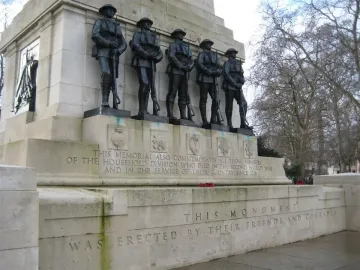 Guards Memorial with five dark soldier figures standing on a stone pedestal with engraved dedication text below.