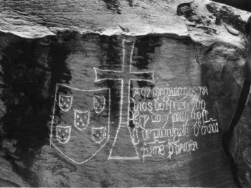 Stone inscription on the Padrão de Ielala with a shield emblem, a large cross, and carved text.