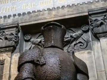 Wehrmann in Eisen, a dark armored knight statue with a sword held horizontally across its lower body.