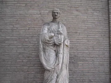 Abbot Luigi, a weathered stone statue of a robed male figure on an inscribed plinth.