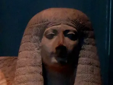 Head and upper torso of Amenia sculpture with heavily lidded eyes and a large textured wig