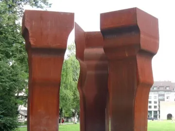 Buscando la Luz II by Eduardo Chillida, three rusted steel sculptures standing in a grassy park.