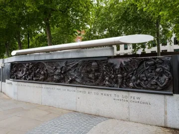 Battle of Britain Monument bronze relief panel with figures, a domed building under attack, and a Churchill quote on the stone base.