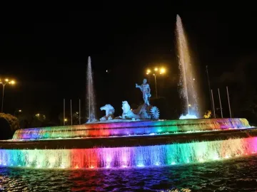 The Fountain of Neptune lit with rainbow-colored water jets at night.