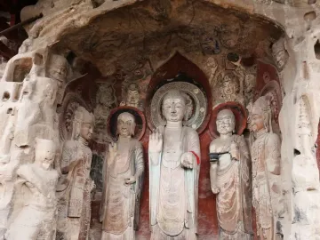 Ancient rock carvings at Huangze Monastery, including a large central haloed statue surrounded by smaller figures in a cave-like recess.