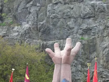 La Mano sculpture with a crowd gathered in front of it, some holding red flags.