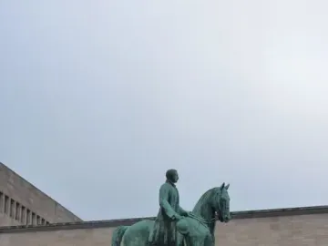 Albert I equestrian statue on a stone pedestal in a public square, with buildings and steps in the background.