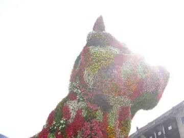 Puppy, a giant dog sculpture covered in colorful flowers, standing outdoors near the Guggenheim Museum Bilbao.