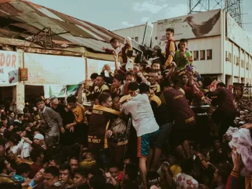 The Black Nazarene statue is carried through a dense crowd of devotees in the street.