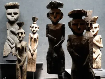 Chemamull wooden figures displayed upright on dark bases in a museum gallery.
