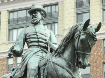Bronze equestrian statue of General James B. McPherson with a raised horse leg, set against modern buildings.