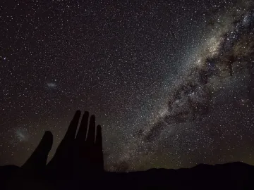 La Mano del Desierto silhouetted against a star-filled night sky and the Milky Way.