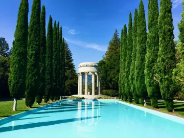 Pulgas Water Temple reflected in a still reflecting pool, with a lone person standing nearby.