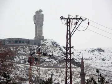 Statue of Humanity, a towering concrete sculpture of two abstract human figures beside a circular building in snowy Kars.