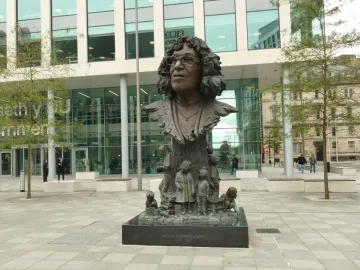 Betty Campbell statue showing a bronze bust of a bespectacled woman on a tall base, with small bronze figures and books around it.