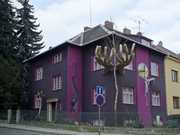 Kristek House in Brno with a dark purple facade, pink window accents, and surreal sculptural elements including large hands and a melting clock.