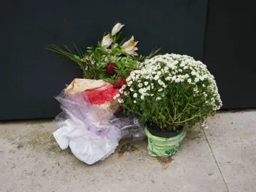 Floral tributes placed before the National Police Memorial, including bouquets and a potted plant with small white flowers.