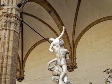 The Rape of the Sabine Women marble sculpture shows three intertwined figures in a dynamic pose inside an arched loggia.