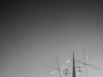 Ad Astra sculpture with slender spire and radiating metal rods against a bright sky.